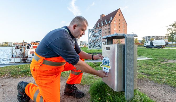 René Siegel von der SAS befestigt am Papierkorb neben dem Relief „Vogelzug“ einen Aufkleber mit dem QR-Code Fotos: maxpress/srk