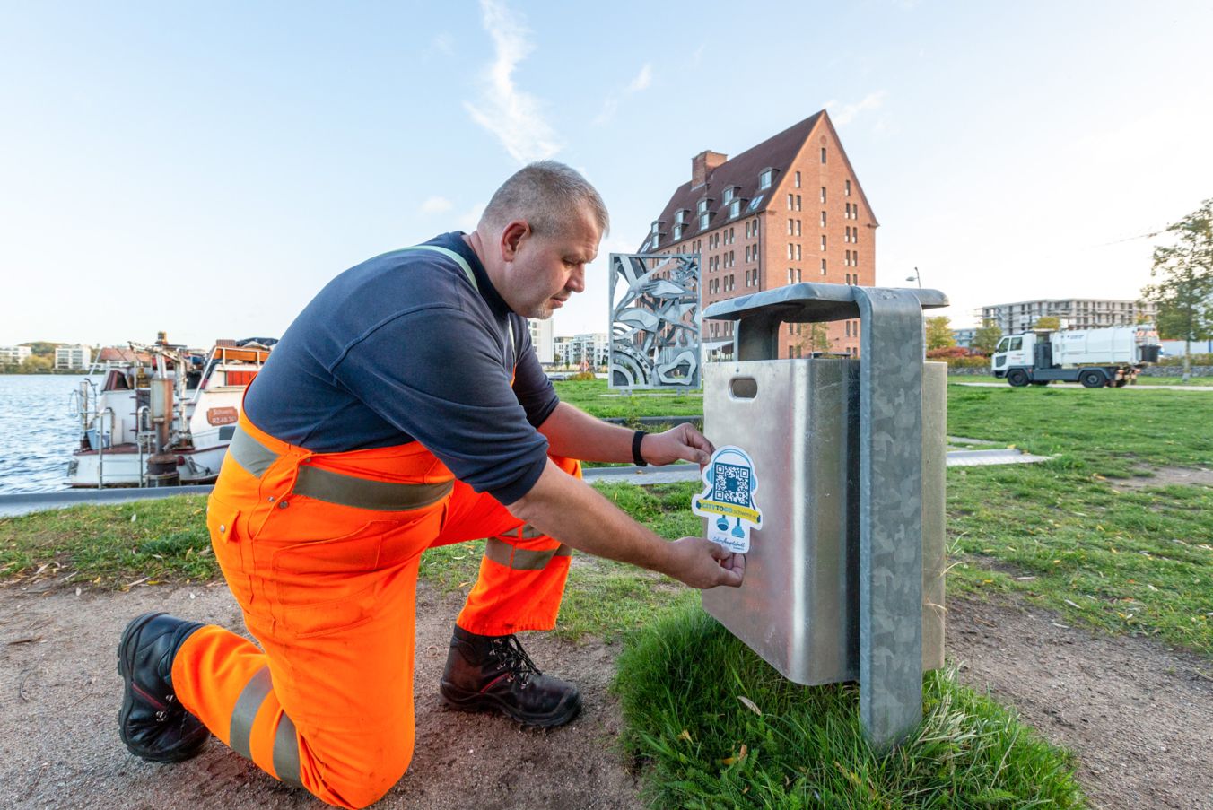 René Siegel von der SAS befestigt am Papierkorb neben dem Relief „Vogelzug“ einen Aufkleber mit dem QR-Code Fotos: maxpress/srk