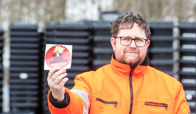 Stephan Wilmer zeigt die roten Warnaufkleber für die Mülltonnen, Foto: maxpress/srk